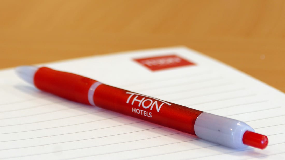 Pen on writing pad. Both with Thon Hotels logo.