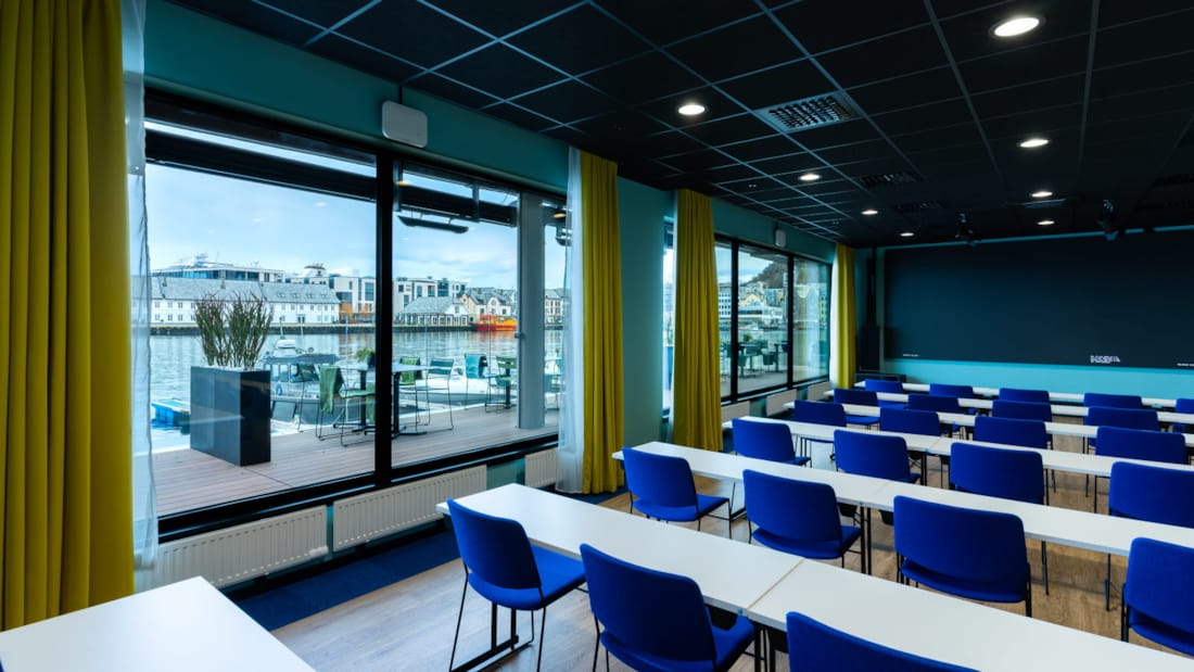 Konferenzraum im Klassenzimmer-Layout mit großen Fenstern und Tafel