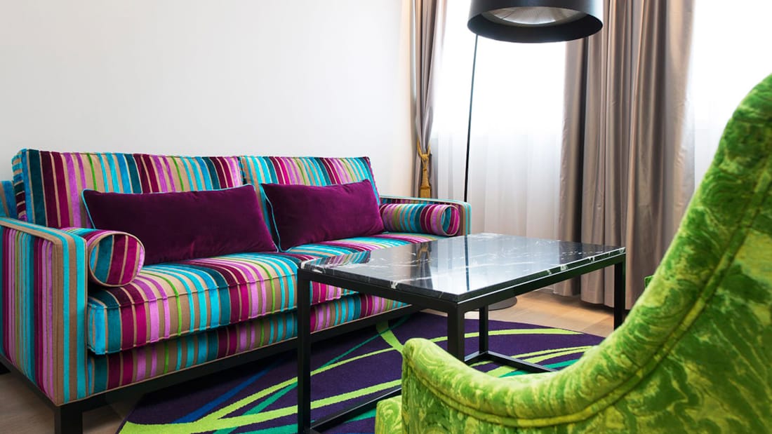Junior Suite med fargerik sofa og teppe, stuebord og grønn lenestol