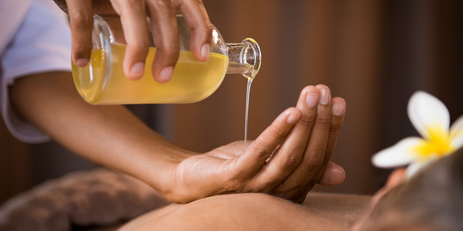 Massage oil being poured on hand in a relaxing atmosphere