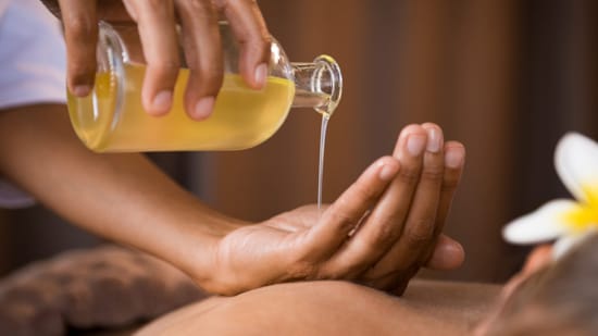 Massage oil being poured on hand in a relaxing atmosphere