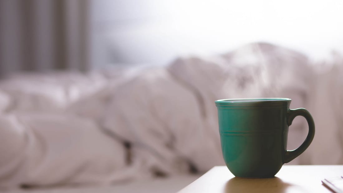 Coffee cup on bedside table in hotel room