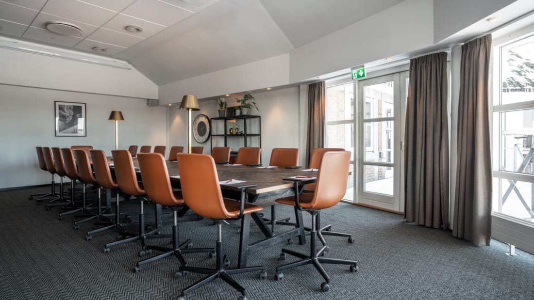 Salle de réunion avec de grandes surfaces vitrées. Groupes avec tables et chaises. 