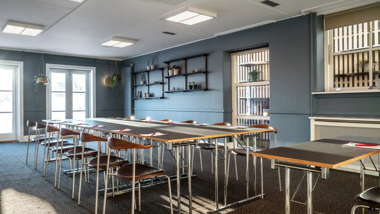Espace de réunion avec une table avec pause repas à gauche et une table avec tabourets de bar à droite.