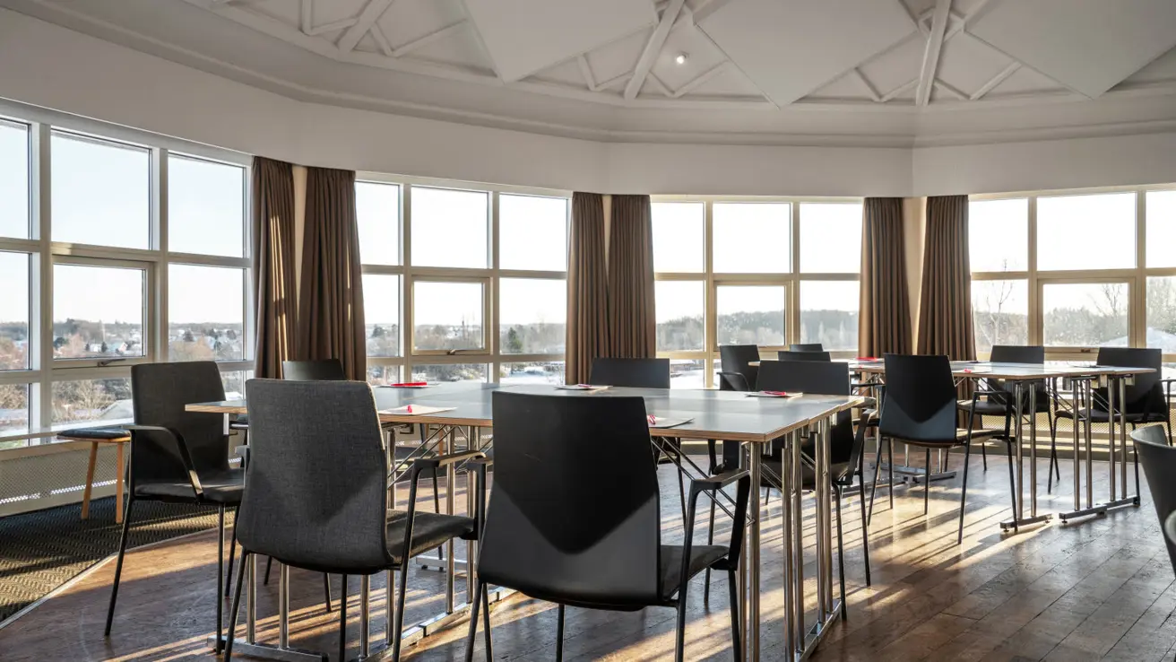 Grande salle de réunion avec toit en forme de dôme et grandes surfaces vitrées. Groupes avec tables et chaises.