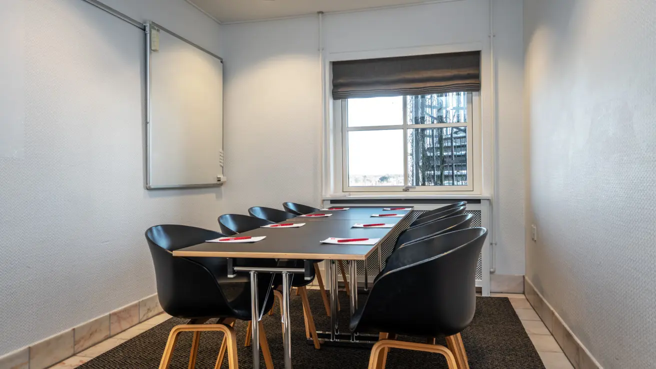 Gros plan des tables et des chaises dans la configuration de salle de classe. Il y a des stylos et du papier sur les tables