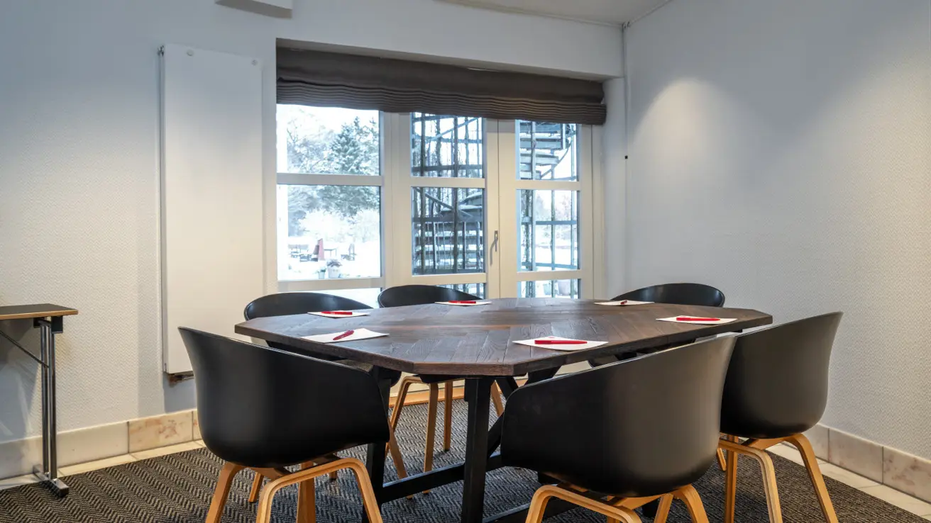 Gros plan des tables et des chaises dans la configuration de salle de classe. Il y a des stylos et du papier sur les tables