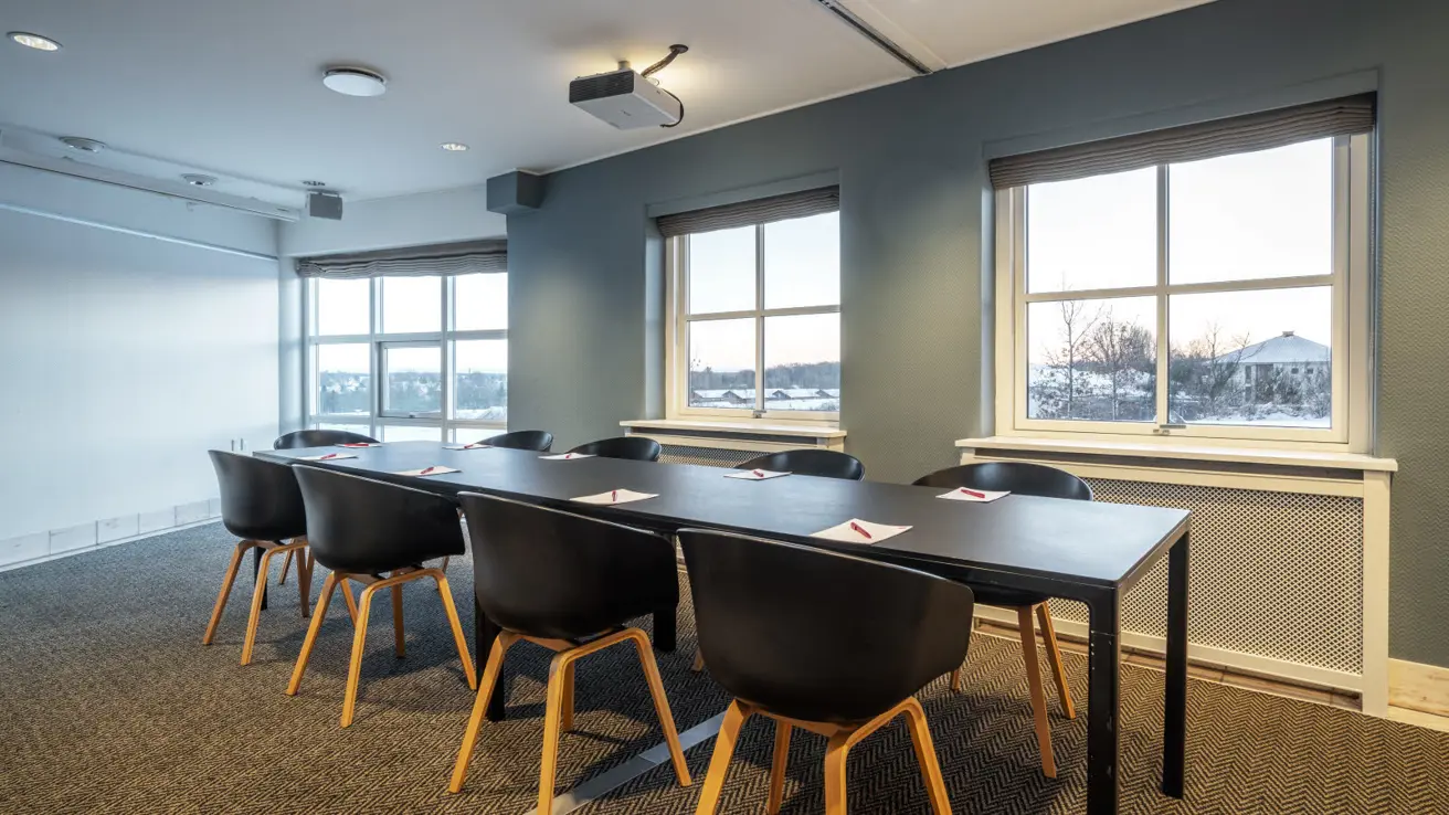 Gros plan des tables et des chaises dans la configuration de salle de classe. Il y a des stylos et du papier sur les tables