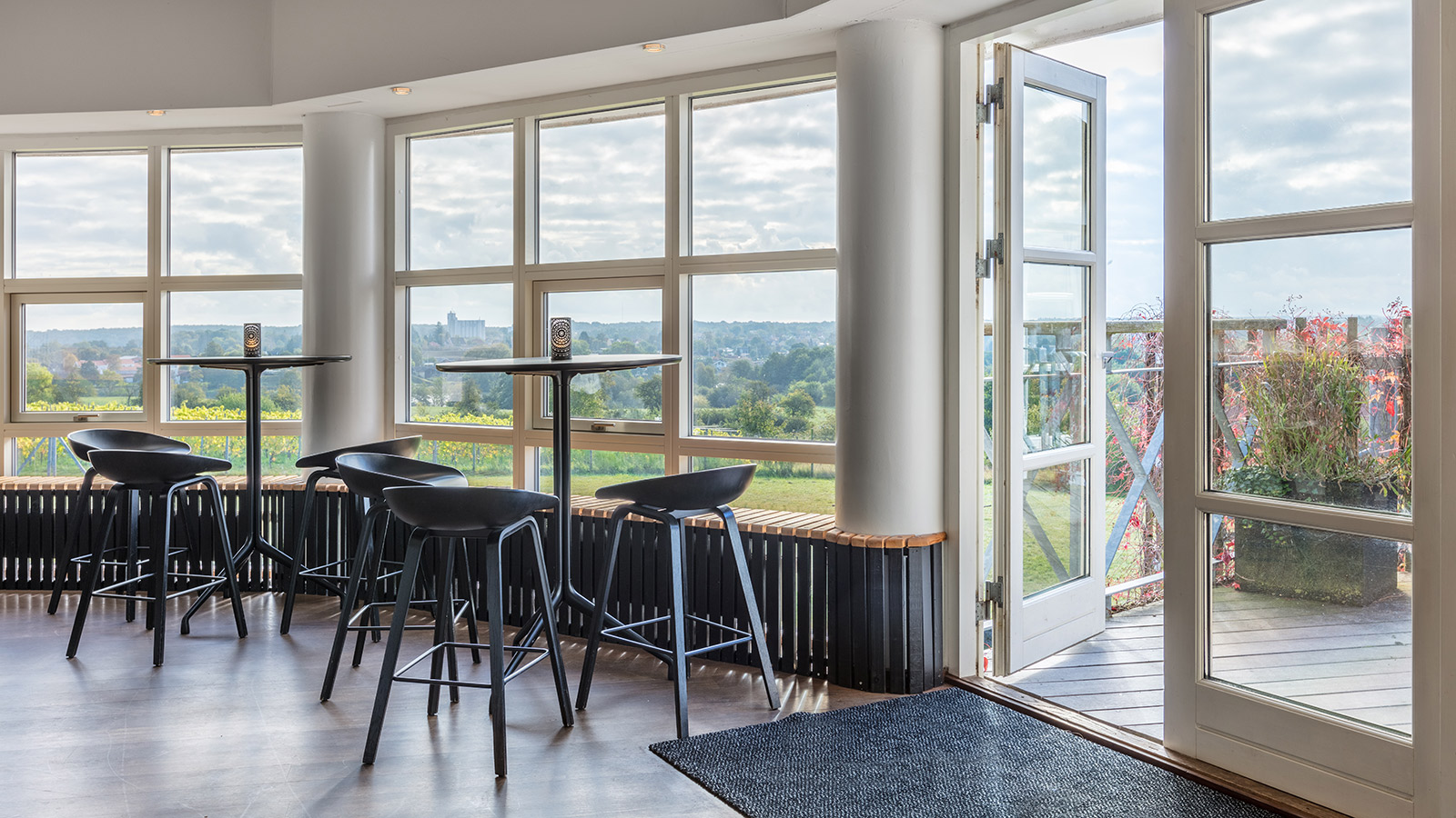 Barstoler og bord foran vinduer med utsikt over hage