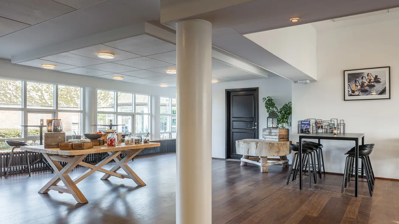 Pauseområde med bord med mat til venstre og barstoler og bord til høyre