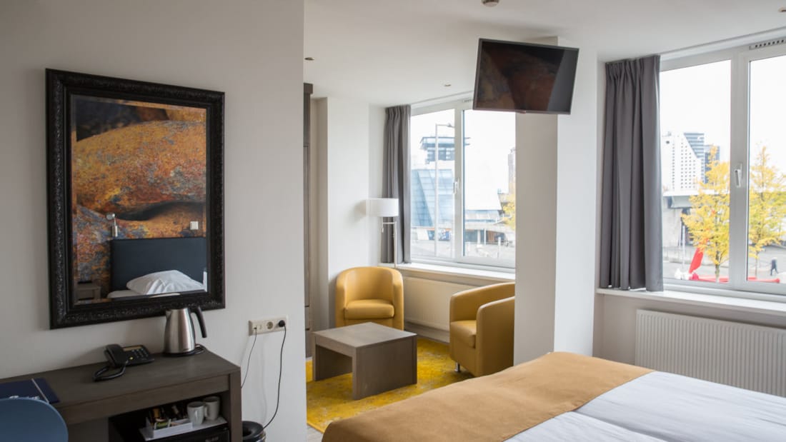 superior room med tv, maleri, gule lenestoler, dobbeltseng og elveutsikt