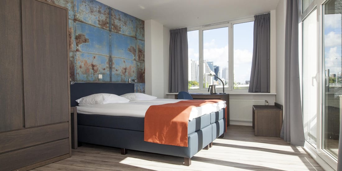 Double bed in superior room with a view over the river Maas