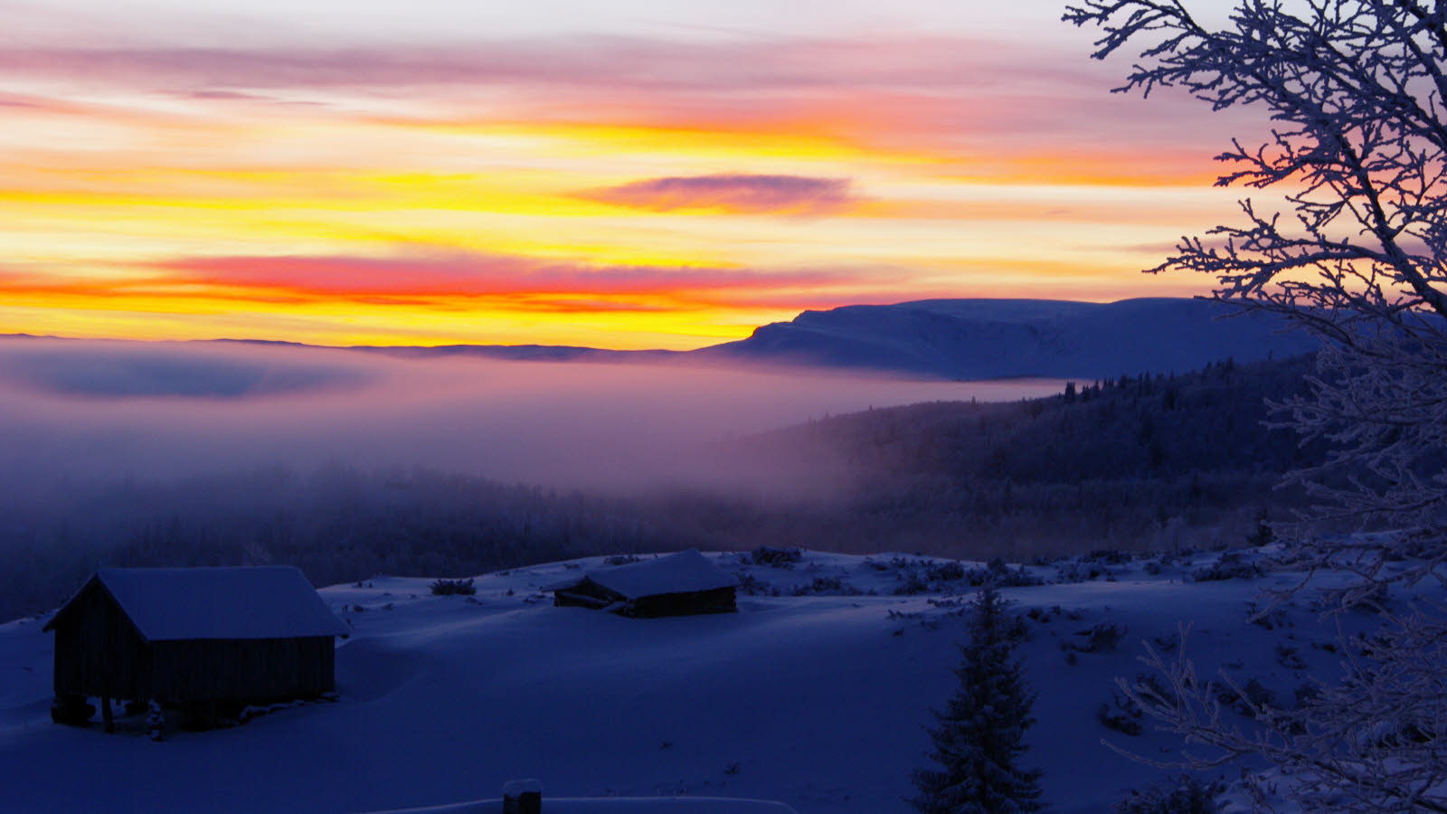 Schneebedeckte Landschaft mit Häusern im Vordergrund.