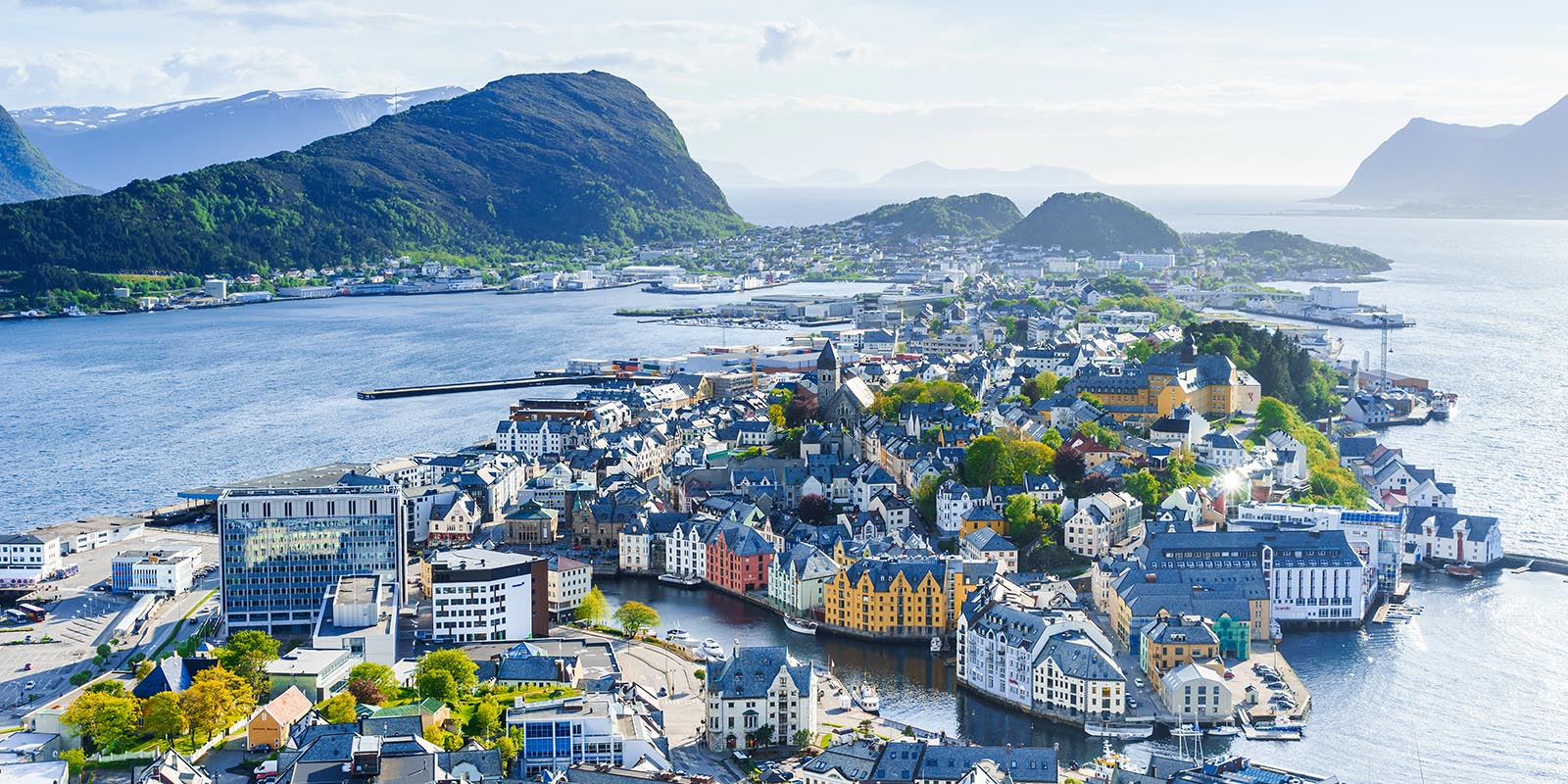 Utsikt över hela Ålesund med fjord och berg i bakgrunden.