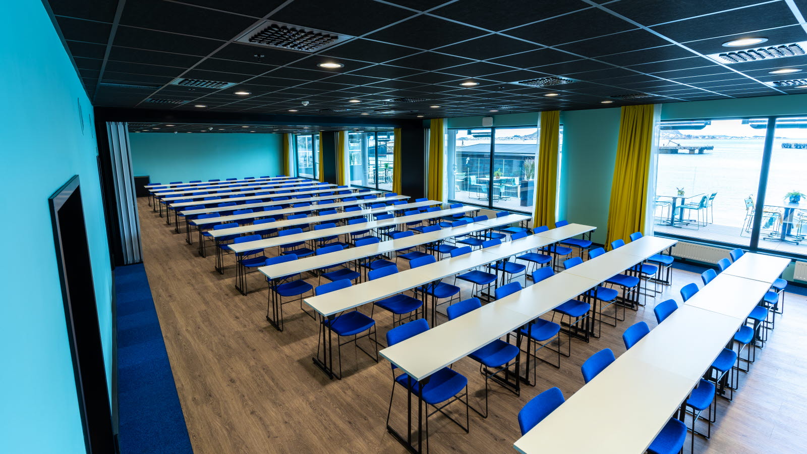 Salle de conférence en salle de classe avec chaises bleues et grandes fenêtres