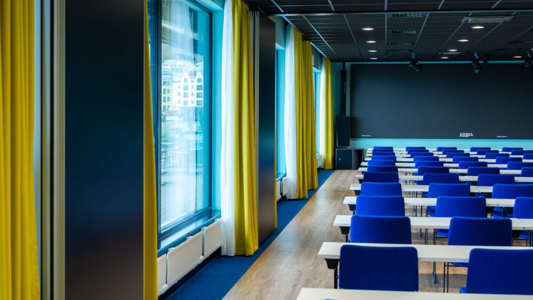 Conferentieruimte met grote ramen en blauwe stoelen