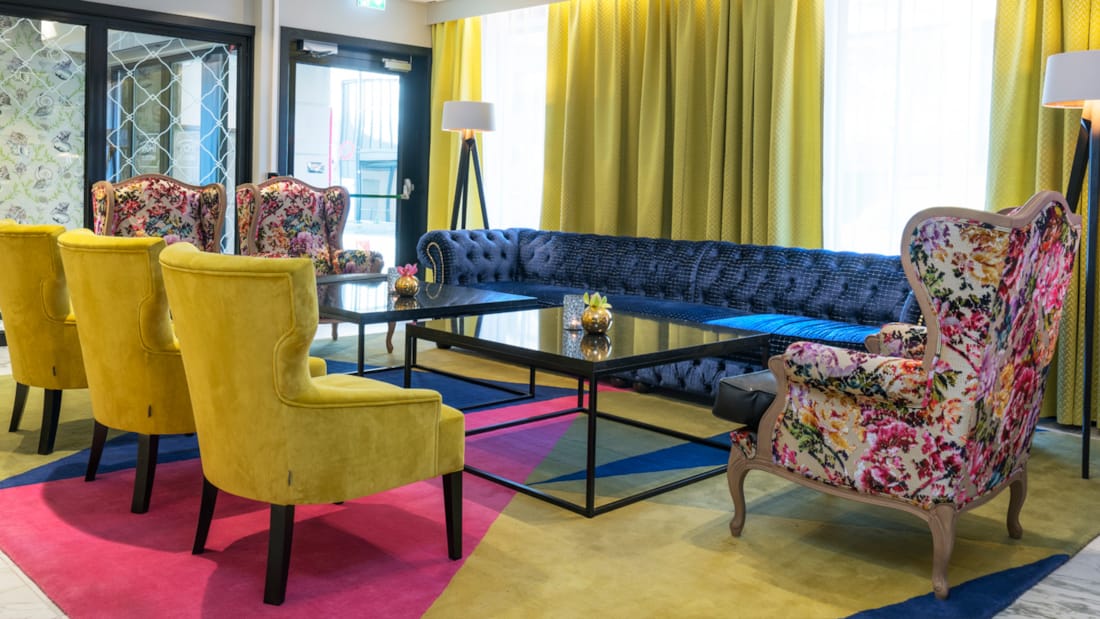 Farverig lobby med bløde stole og sorte borde i rummelige omgivelser