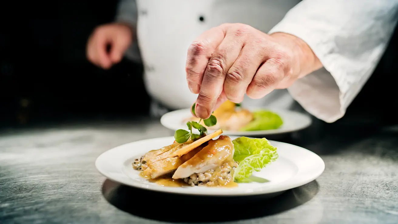 Cuisinier préparant une assiette de risotto et de poulet dans la cuisine
