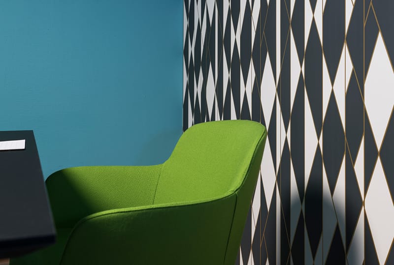 Mødelokale med sort- og hvidmønstret tapet og grøn stol med blå væg