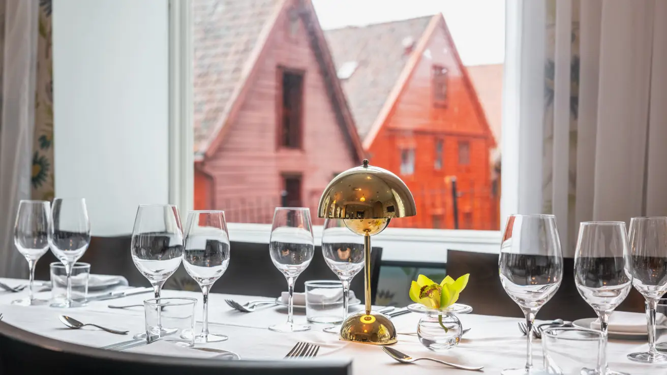 Nærbilde av bord dekket til selskapsmiddag. I bakgrunnen ses utsikt mot baksiden av Bryggen.