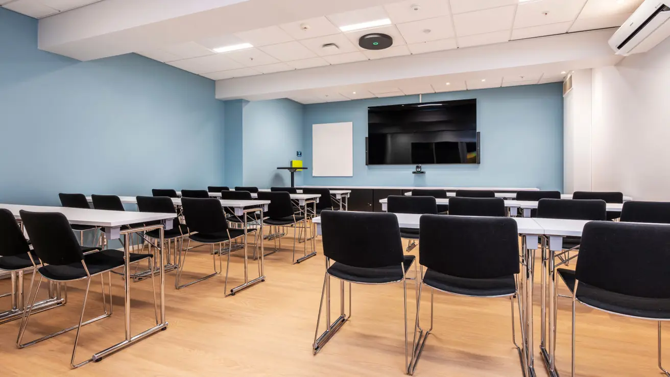 Møterom i klasseromsoppsett. Skjerm og whiteboard i front.