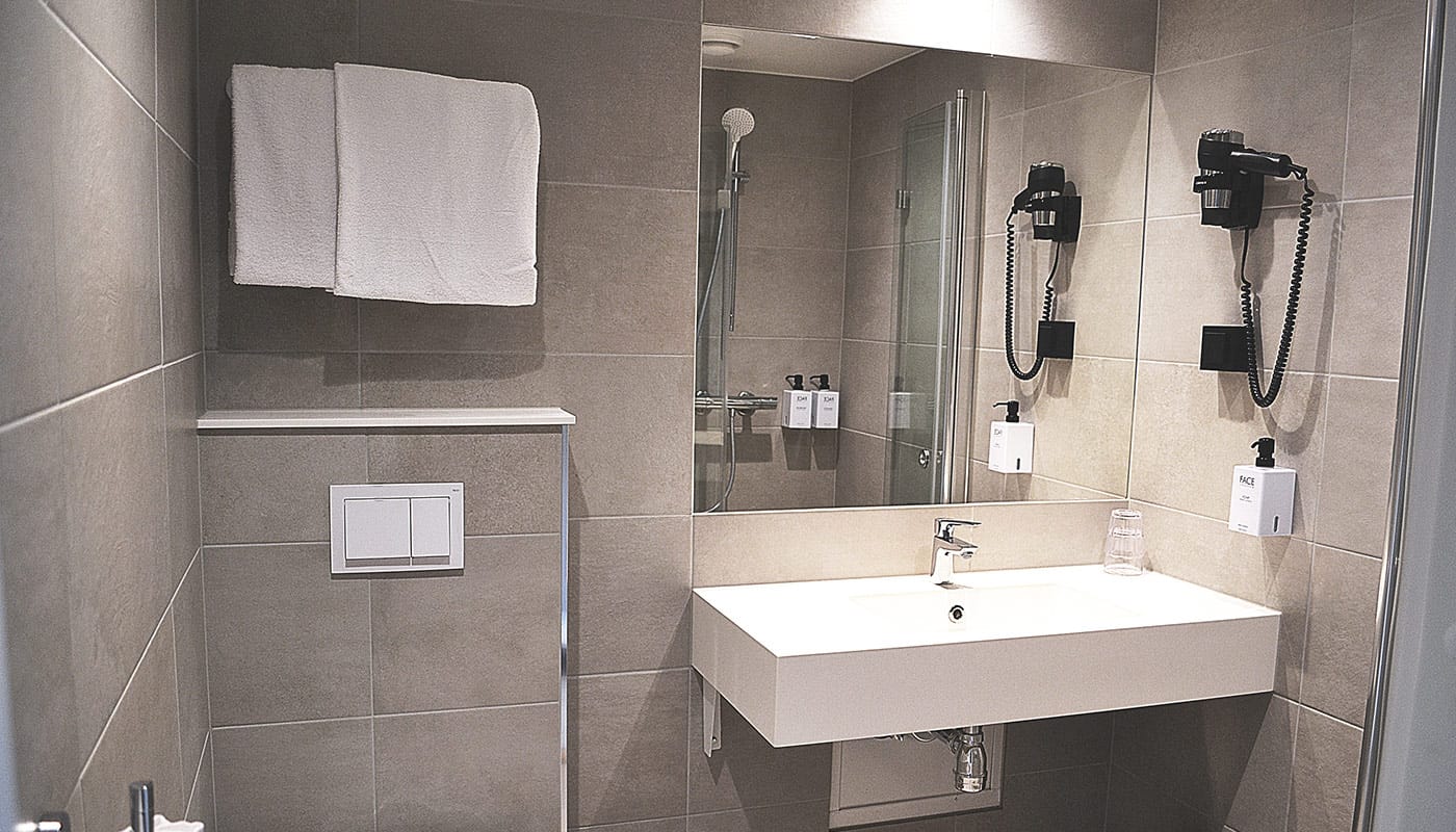Lavabo et miroir de salle de bain dans la chambre familiale de l’Hotel Central d’Elverum 