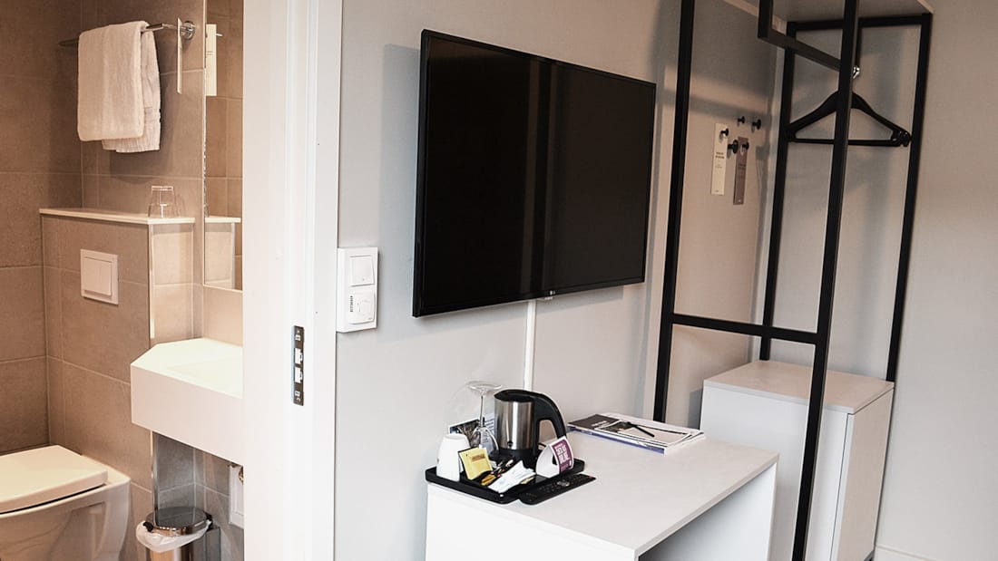Tv og dele af badeværelse i enkeltværelse på Hotel Central i Elverum
