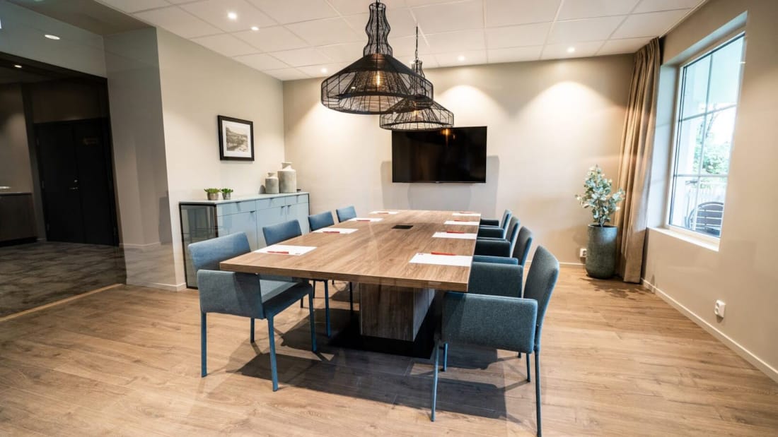 Lyst og moderne konferencelokale med hovedbord og blå stole