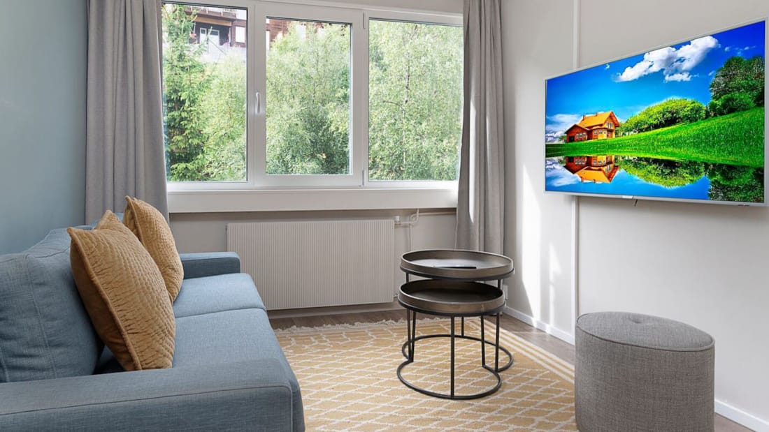 Blå sofa med puter i lyst rom foran TV