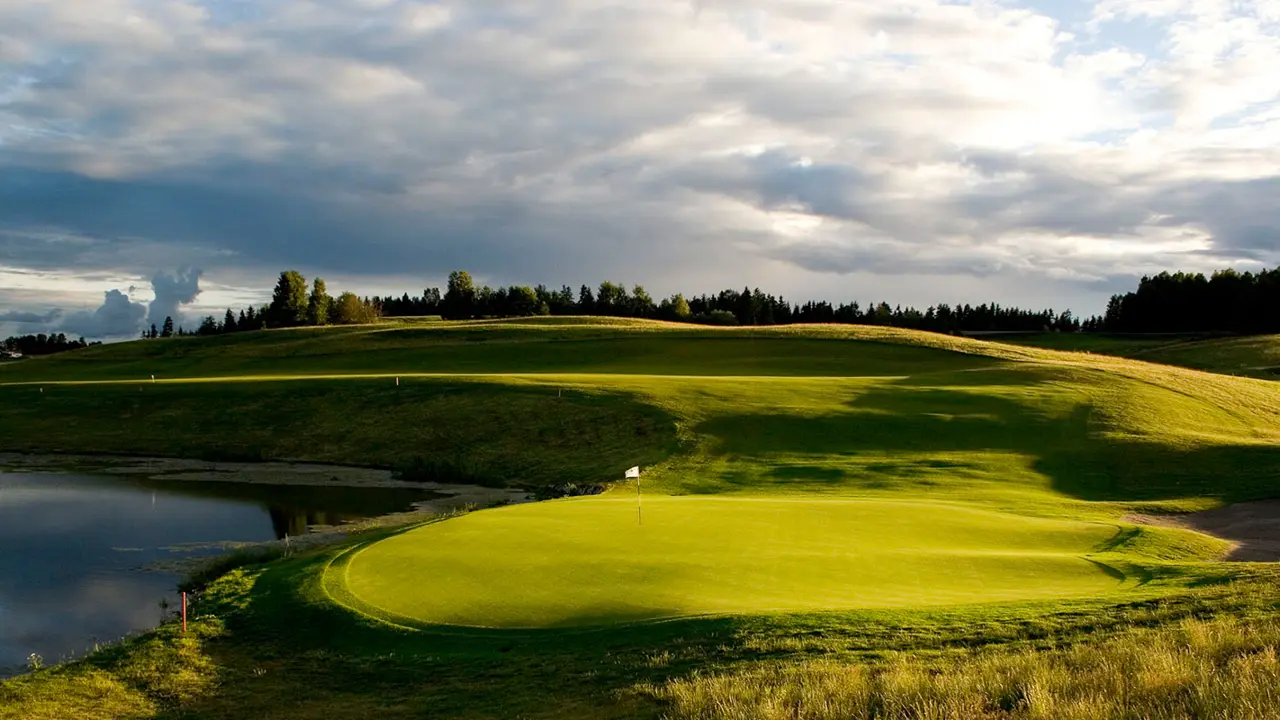 Un terrain de golf avec un étang et de l’herbe verte.