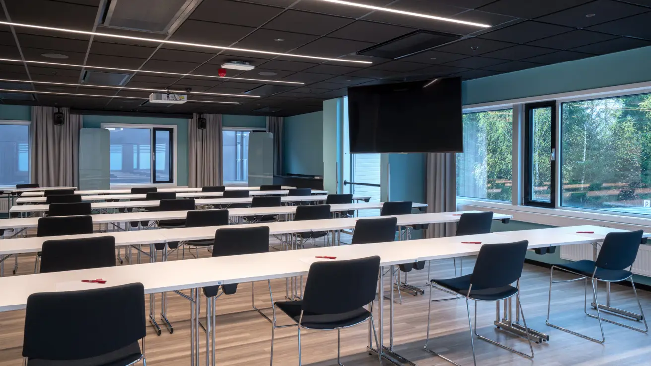 Stort og luftig konferanserom med bord og stoler i klasseromsoppsett.