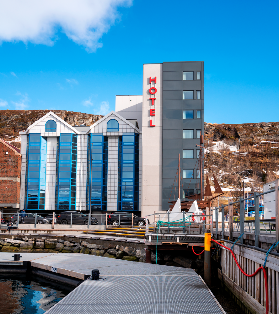 La façade du Thon Hotel Hammerfest vue de la zone portuaire. Ciel bleu en arrière-plan. 