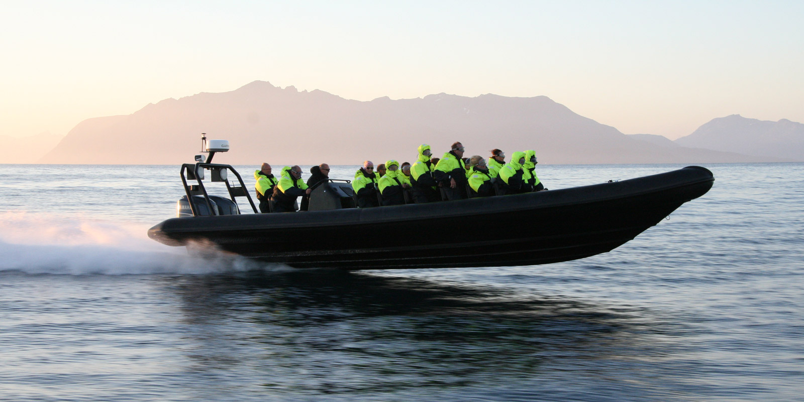 Ribbåt med mennesker som kjører på vannet i Harstad