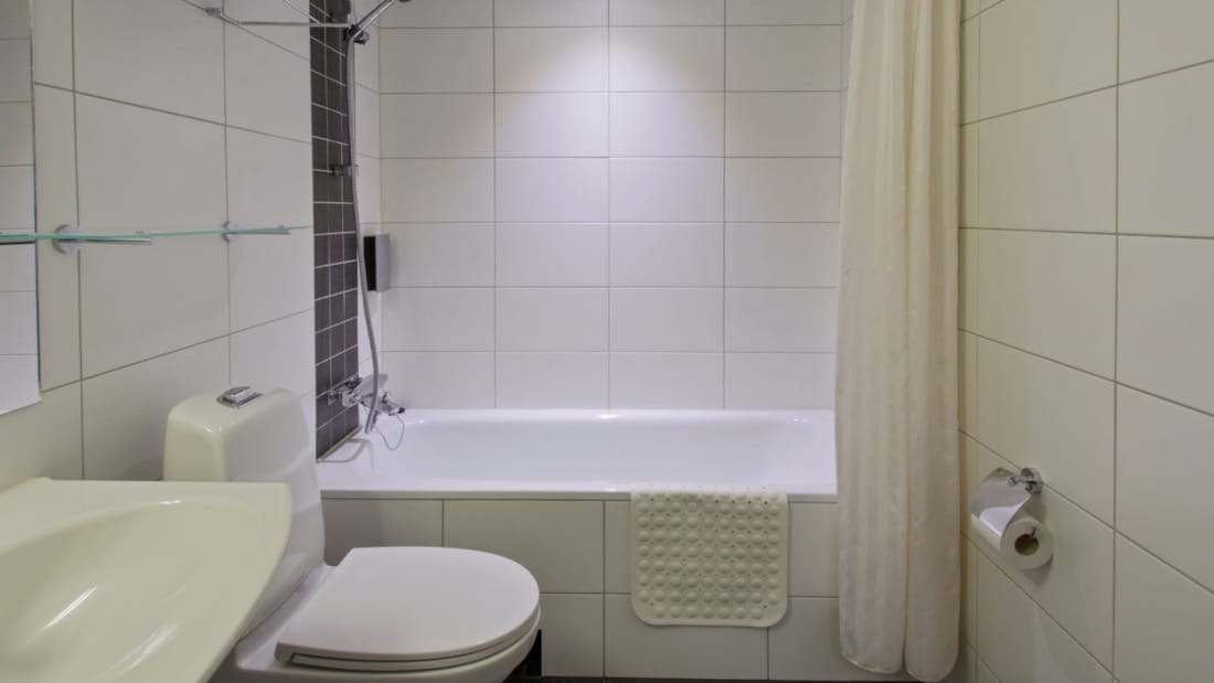 Badekar med bruser, toilet og håndvask i badeværelse i Superior room på Hotel Horten