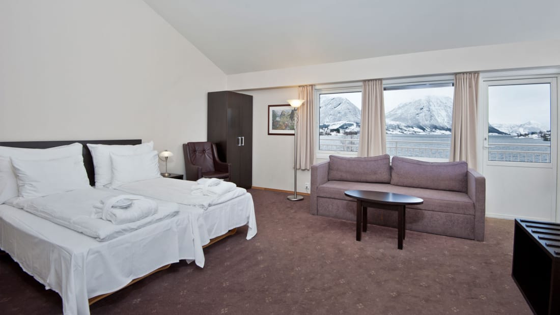 business room säng, stol, soffgrupp samt utsikt över berg och hav