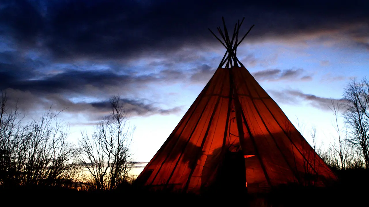 En teepee vises i mørket med en mørk himmel.