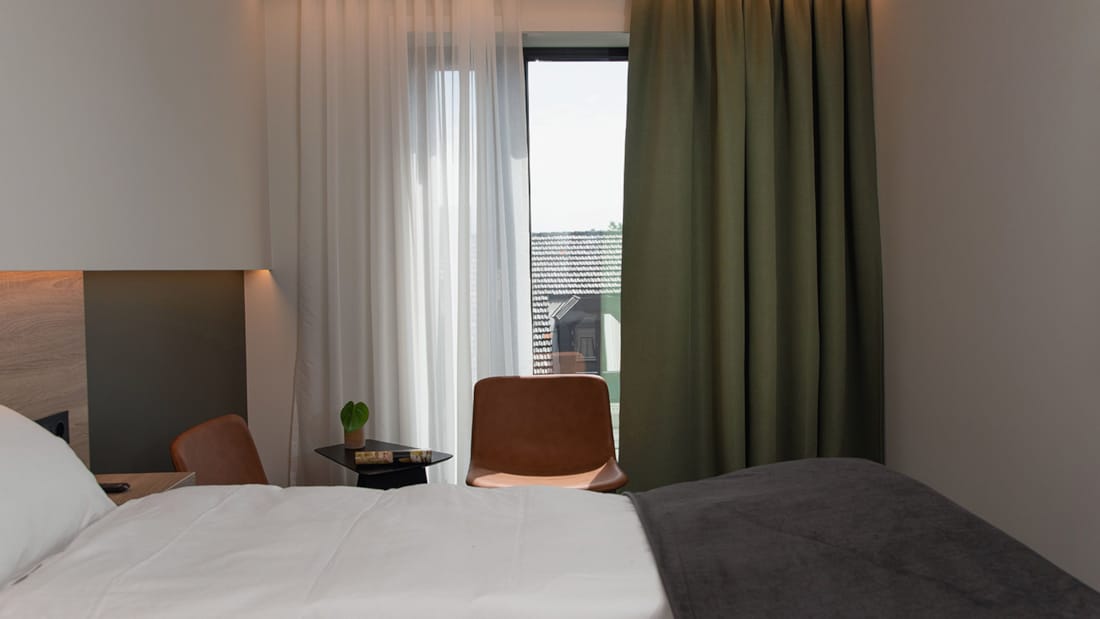 Dobbeltseng og stol i dobbeltværelse på Hotel Norge