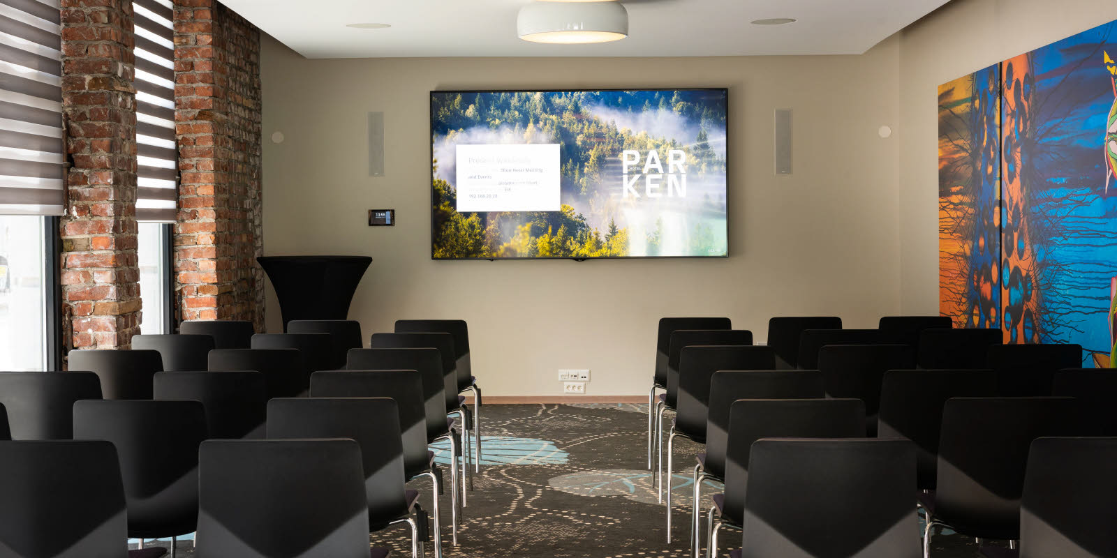 Eik konferencelokale med biografopsætning set mod skærm