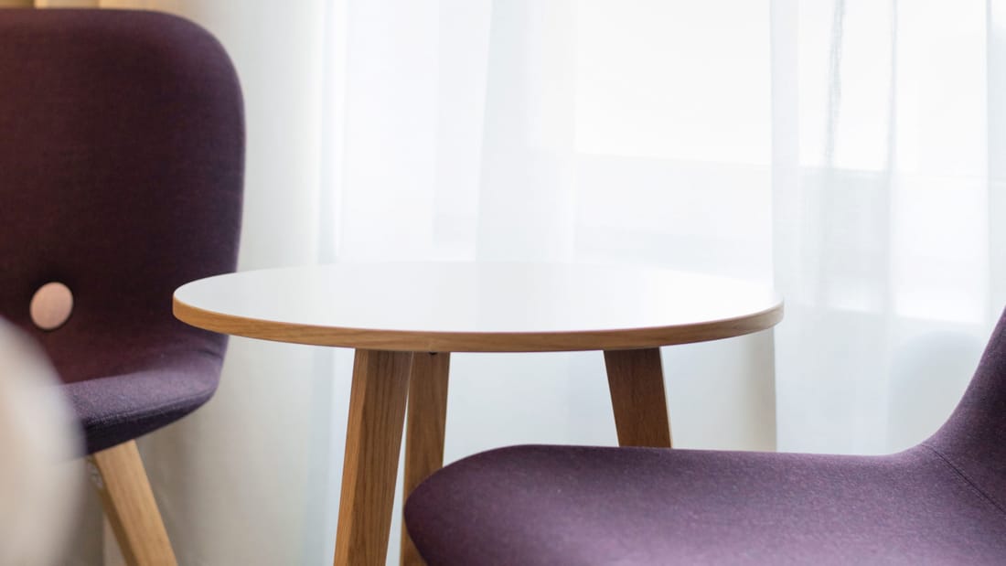 Rum med två lila fåtöljer och minimalistiskt bord på Hotel Parken i centrala Kristiansand