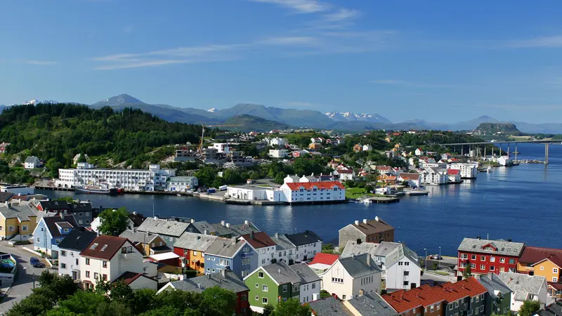 Panoramic view of colourful houses and water in Kristiansund. Blue sky and mountains in the background