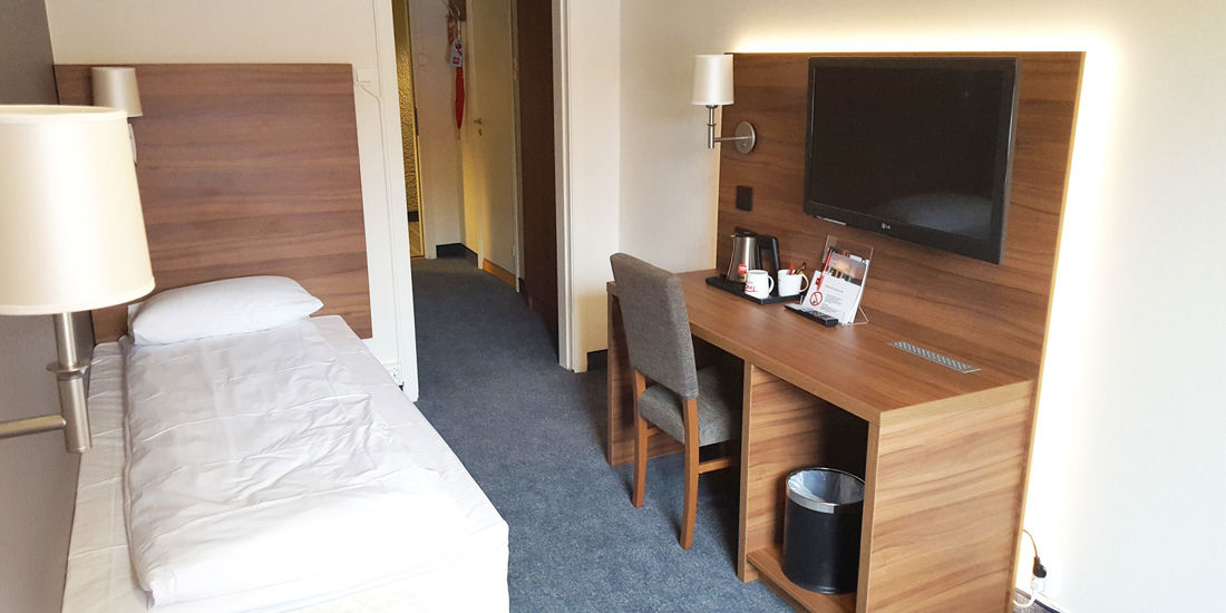 Hotelbett mit Kaffeetasse auf dem Nachttisch