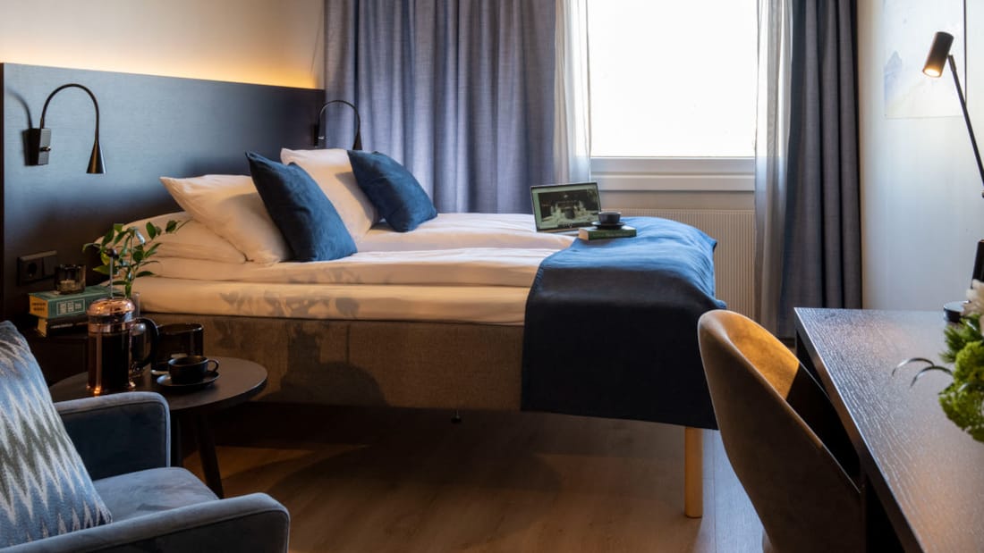 Säng, bord och soffa i rum på Hotel Backlund