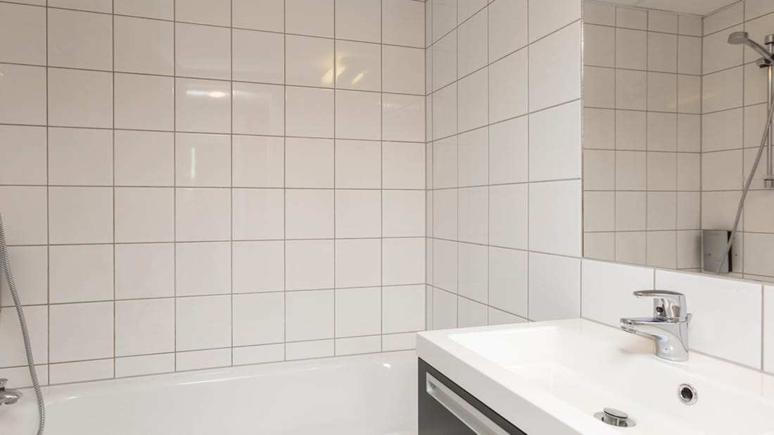 Håndvask og bruser med badekar i værelse på Hotel Backlund