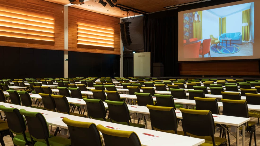 Norgessalen med projektor og gule og grønne stole på Thon Hotel Arena i Lillestrøm