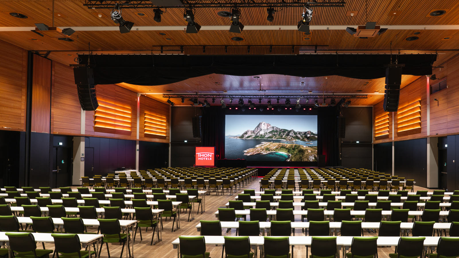 Stor konferansesal i klasseromsoppsett og med skjerm i front.