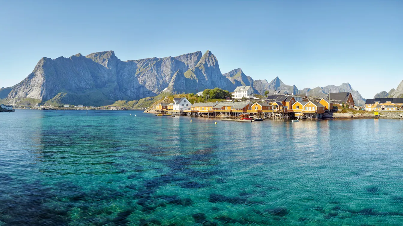 Gula hus på brygga i Lofoten med hav och fjäll runt omkring. 