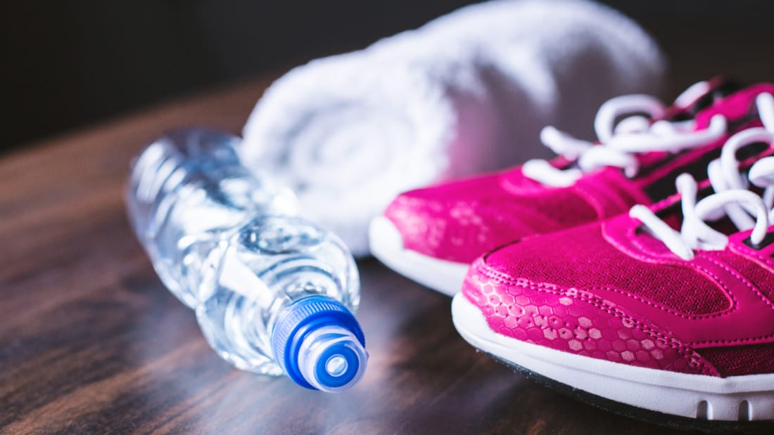 Picture of water bottle, rolled towel and sneakers.