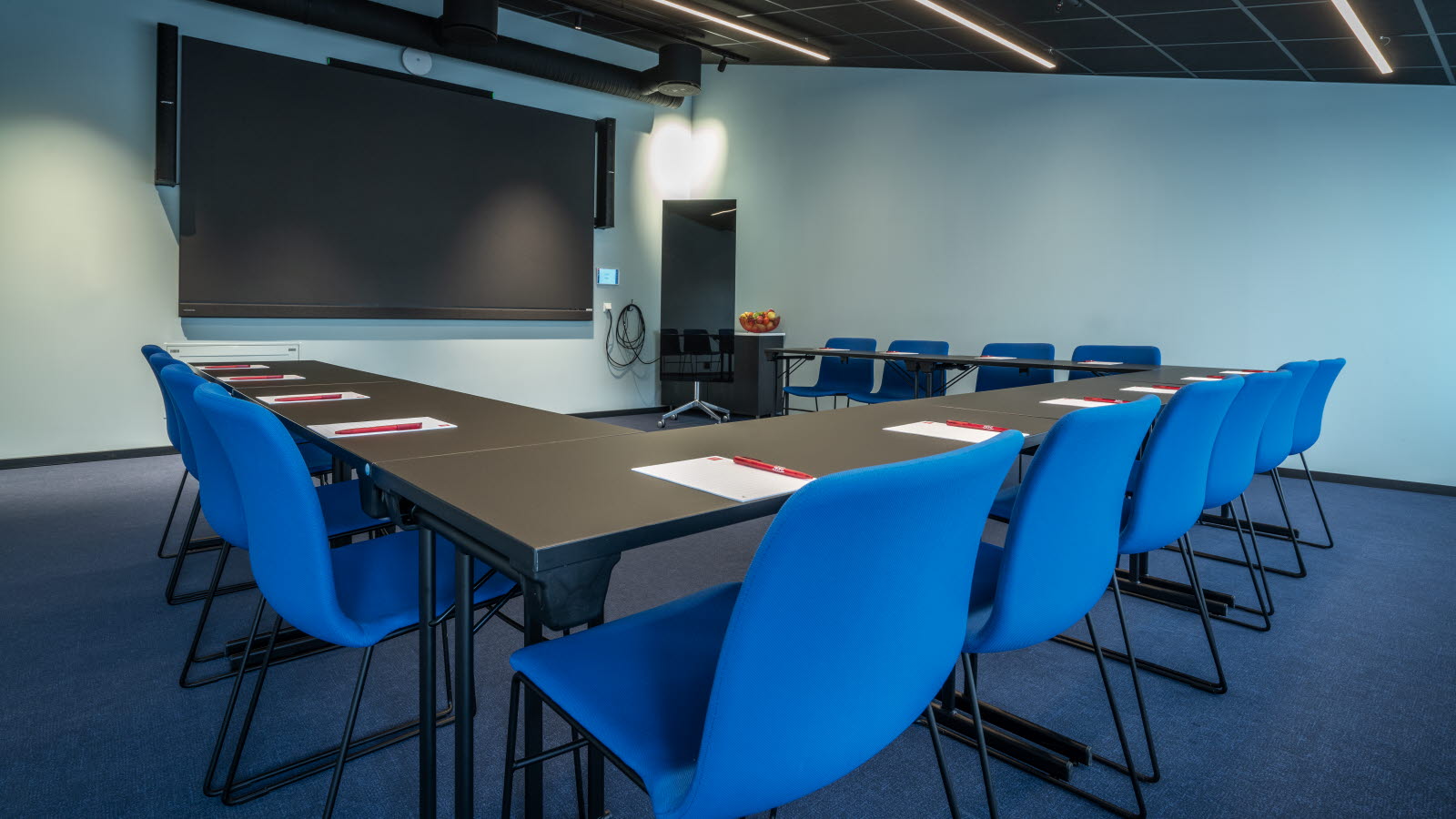 Møterom Røst med blå stoler og tv skjerm