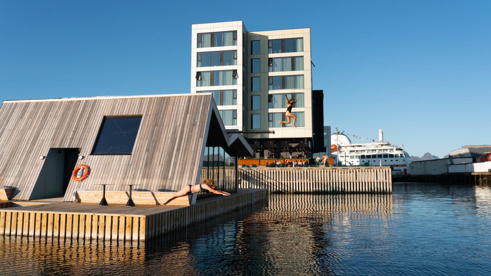 To kvinner stuper og hopper fra den flytende badstua utenfor Thon Hotel Svolvær.