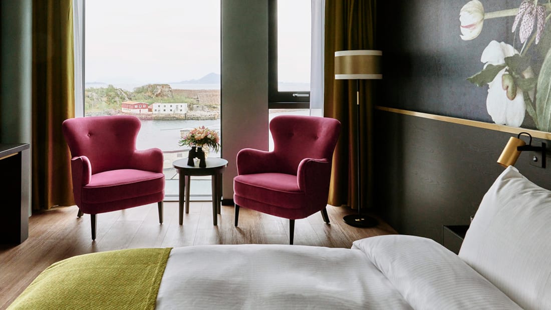 Seng og stole foran vindue i superior room på Thon Hotel Svolvær